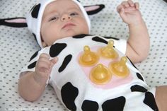 a baby wearing a cow costume laying on top of a bed