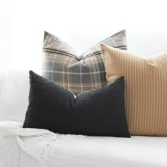 three pillows sitting on top of a white couch