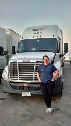 a woman standing in front of two semi trucks