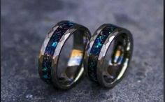 two wedding rings with blue and green glitters on the inside, one is black