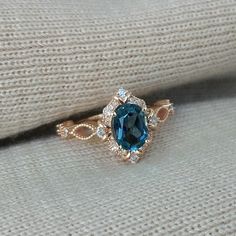 a blue diamond ring sitting on top of a white sweater