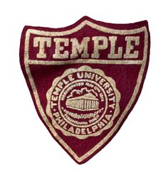 a red and gold patch with the word temple on it's side, in front of a white background