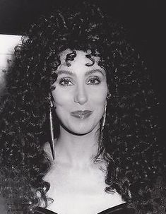 a black and white photo of a woman with long curly hair wearing large hoop earrings