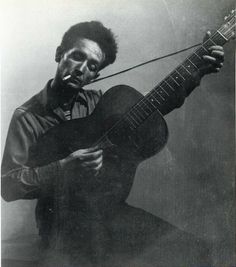 a black and white photo of a man holding a guitar