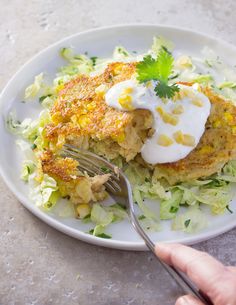 a white plate topped with crab cakes covered in sour cream and garnished with lettuce