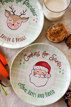 two plates with christmas designs on them next to some carrots and cracker sticks