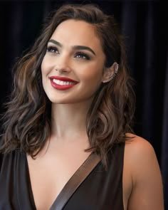 a woman in a black dress smiling at the camera with red lipstick on her lips