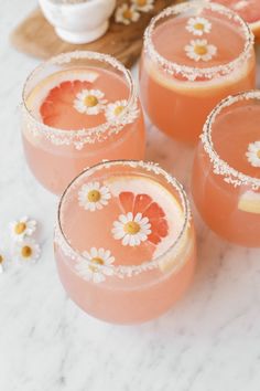 four glasses filled with pink liquid and garnished with flowers