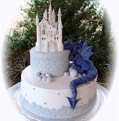 a white cake with blue icing and a dragon on top