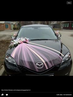 a black car decorated with flowers and ribbons