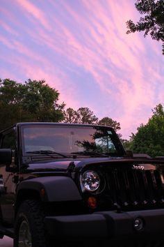 the jeep is parked on the side of the road with trees in the back ground