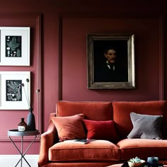 a living room with red walls and pictures on the wall, including an orange couch