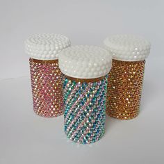 three jars with different colored sequins on them