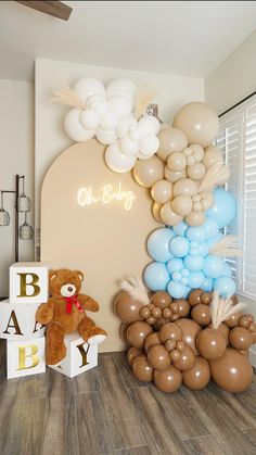 balloons and teddy bears are displayed in front of a baby's name sign on the wall