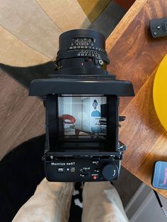 a person holding a camera up to take a photo with their feet on the table