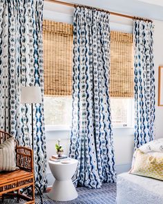 a white toilet sitting next to a window in a room with blue and white curtains