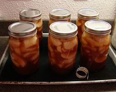 six jars filled with pickles sitting on top of a counter