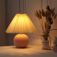 a white lamp sitting on top of a table next to a vase filled with flowers