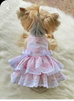 a small dog wearing a pink dress on top of a white furnishing floor