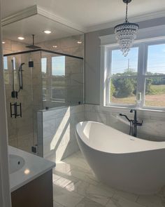 a bathroom with a large bathtub next to a walk in shower and a chandelier