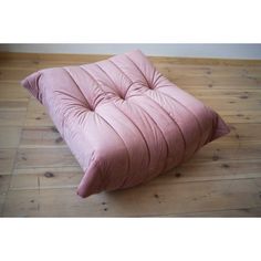 a pink cushion sitting on top of a wooden floor