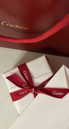 an open box with a red ribbon on it and a white card in the middle