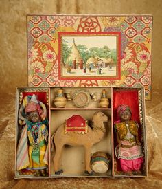 an open box with figurines in it on a brown cloth covered tablecloth