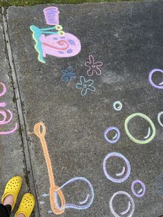 someone is standing on the sidewalk with chalk drawings and crayons in front of them