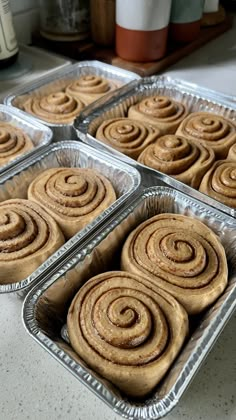 four pans filled with cinnamon rolls sitting on top of a counter