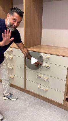 a man standing in front of a cabinet with drawers