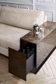 a coffee table with an open drawer in front of it on a wooden floor next to a couch