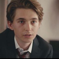 a young man in a suit and tie looking at the camera with serious expression on his face