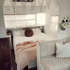 a white bed sitting next to a window in a bedroom