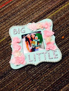 a small blue frame with pink flowers on the bottom and an inscription that says, big little