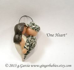 an ornament shaped like a couple kissing each other on a white background with the words one heart above it