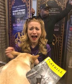 a woman is getting her hair cut by a dog in front of a sign that says,