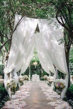 an outdoor ceremony with white drapes and flowers