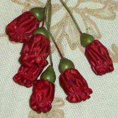 five red flowers with green stems on a white cloth covered tablecloth ornament