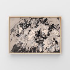 a black and white painting hanging on a wall next to a wooden framed artwork piece