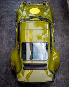 an overhead view of a green car parked on the side of the road with palm trees in the background