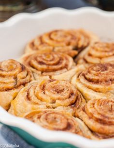 a white dish filled with cinnamon rolls on top of a table