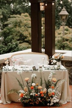 the table is set with flowers and candles for an outdoor wedding reception in front of a gazebo