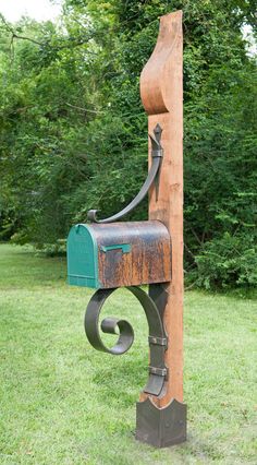 an old mailbox is attached to a wooden post in the middle of some grass