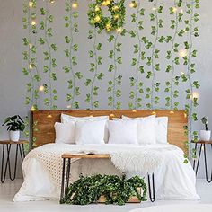 a bed with white pillows and green plants on the wall