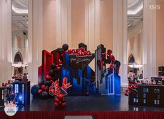 a stage set up for an event with balloons and spiderman decorations on the floor