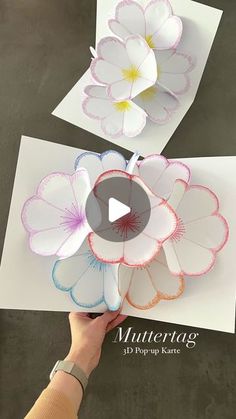 two paper flowers are being held up to show how they have been cut into pieces