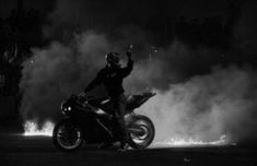 a man riding on the back of a motorcycle in front of a lot of fire