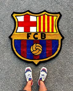 a person standing in front of a soccer emblem on the ground with their feet up