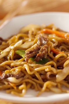 a white plate topped with noodles and meat