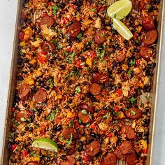 a pan filled with rice, beans and limes on top of a white table